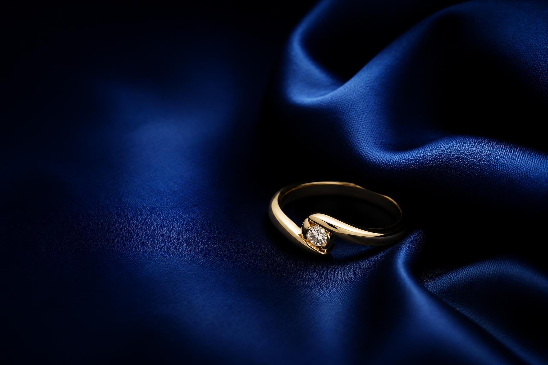 Anillo de oro con diamante sobre seda azul rey